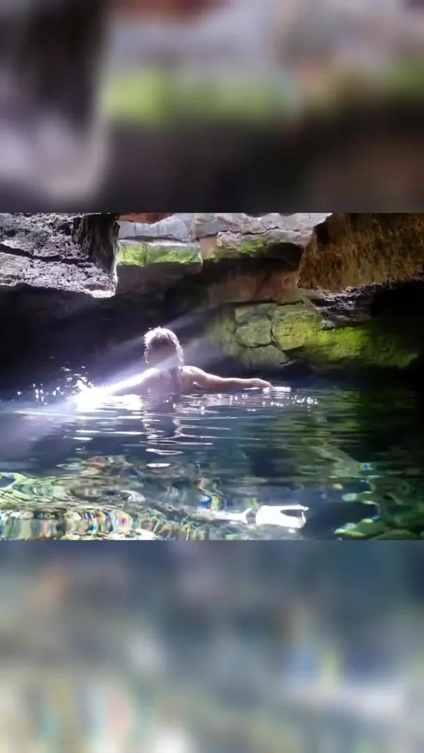 Playful nymph swirling around in the magical light rays in a sacred lava tube