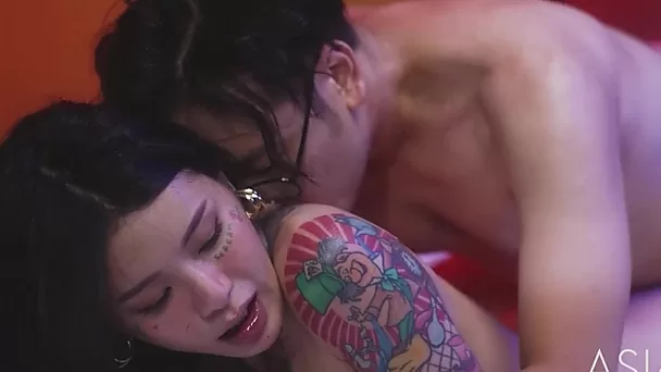 Asian girl with big boobs and tattoos fucks with guy on a large bed