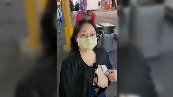 Chica asiática lujuriosa mostró tetas en un lugar lleno de gente en honor a la celebración de halloween.