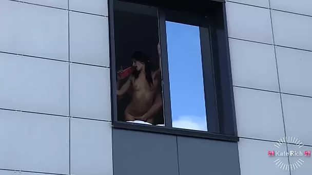 Garota morena magra fica emocionada ao ser fodida perto da janela, sabendo que as pessoas estão olhando para ela