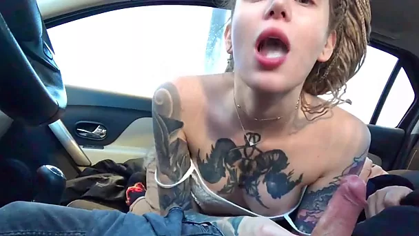 Une fille tatouée avec de beaux seins a séduit son petit ami en voiture et a sucé sa bite dure