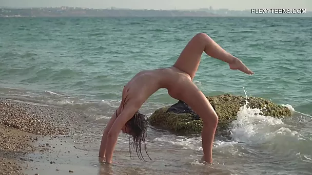 Vergine flessibile fa ginnastica nuda sulla spiaggia - adolescenti flexy