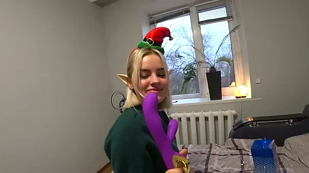 Une elfe de Noël blonde reçoit un cadeau violet et une bite
