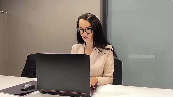 Офисная девушка возбуждается на своем рабочем месте и трет клитор под столом