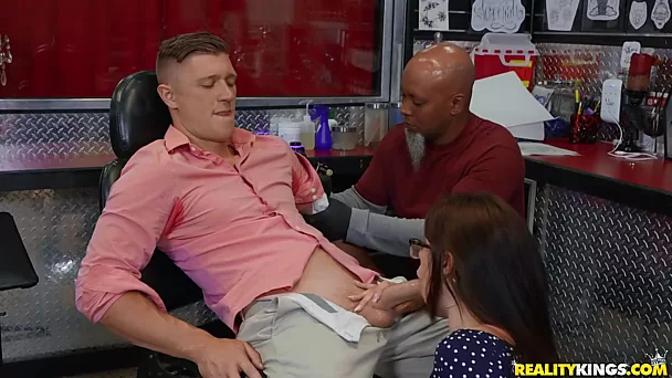 Une pute adolescente aide un mec à se détendre en suçant sa bite tout en se faisant tatouer